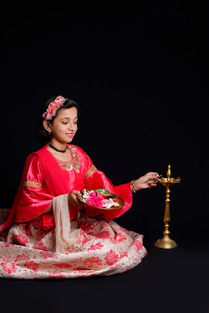 Cute Indian little girl holding diya or oil lamps for Diwali Celebration.