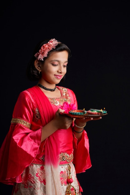 Cute Indian little girl holding diya or oil lamps for Diwali Celebration.