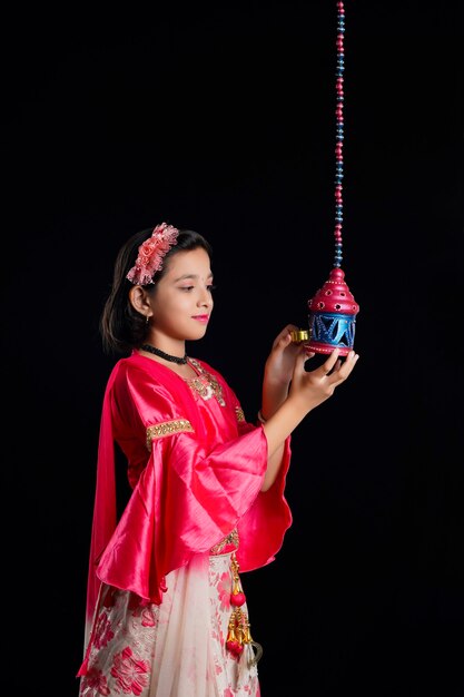 Cute Indian little girl holding diya or oil lamps for Diwali Celebration.
