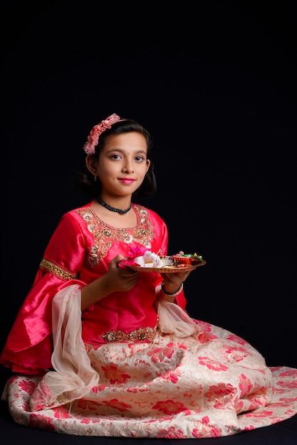 Cute Indian little girl holding diya or oil lamps for Diwali Celebration.