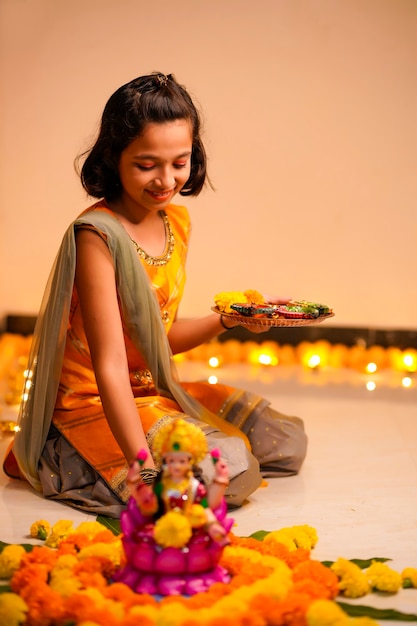 自宅でディワリ祭のために花と石油ランプで装飾を作るかわいいインドの少女。