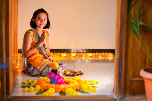 Bambina indiana sveglia che prega e celebra il festival di diwali.