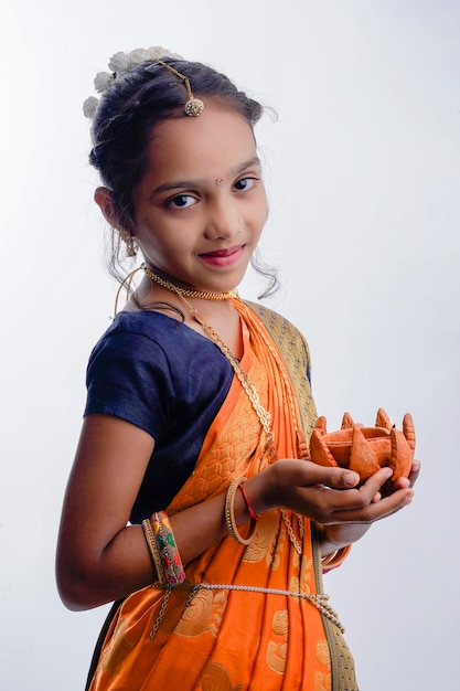 Cute indian maharashtrian little girl holding lamp in hand and celebrate traditional festival Raksha Bandhan or Diwali