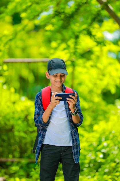 Cute indian schoolboy studying online on smartphone at home