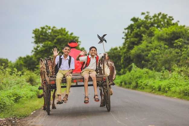 Cute indian schoolboys in a bullock cart