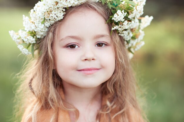 Cute kid girl with flowers in hairstyle outdoor