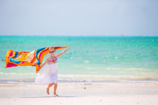 Cute kid having fun running with pareo on tropical beach