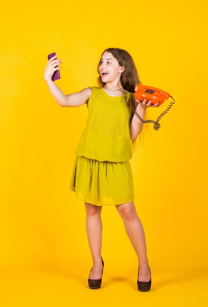 Cute kid hold retro and modern phone for talking, selfie.