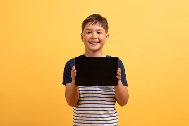 Cute kid holding digital tablet with black empty screen