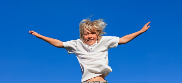 Photo cute kid jumping in the air outdoor