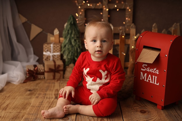 Cute kid in new years pajamas throws a letter to santa claus in\
the mailbox