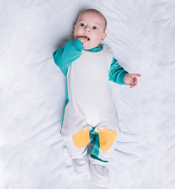 Cute kid in a penguin suit lying on a blanket