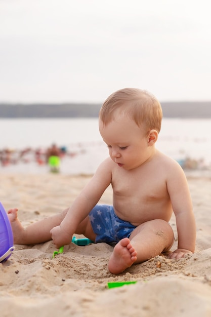 Cute kid playing in the sandbox with toys on the seashore