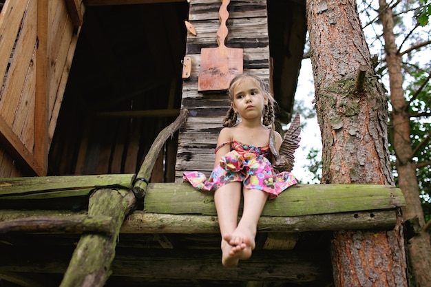 Cute kid sitting alone in the treehouse in summer