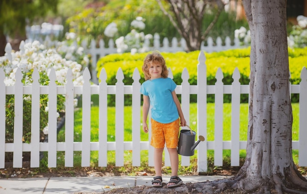 夏の日に庭で花に水をまくかわいい子供夏の日にじょうろを使用して子供