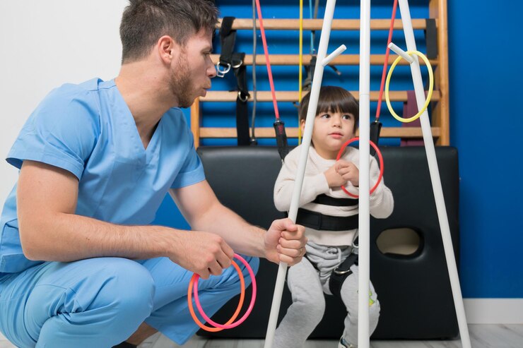 Cute kid with cerebral palsy doing musculoskeletal therapy in the hospital while laughing and having...