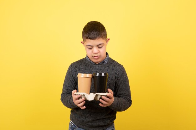 cute kid with down syndrome looking at cups of coffee.