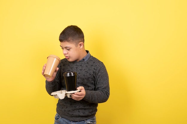 cute kid with down syndrome with cups of coffee standing.