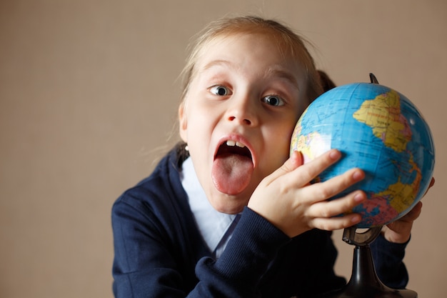 Cute kid with globe showing tongue