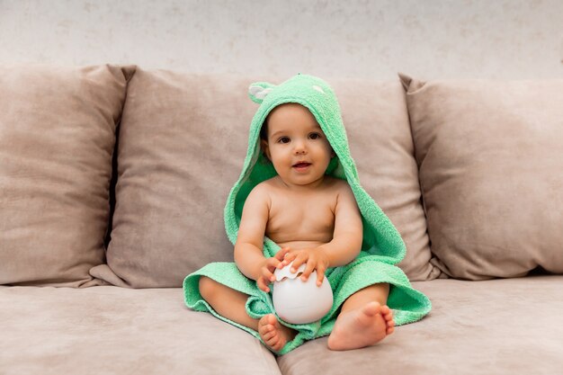 A cute kid wrapped in a towel sits on the bed. baby in a bath towel.