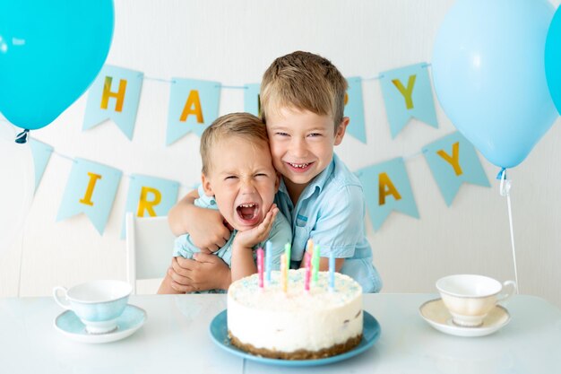 Cute kids kids boys celebrate their birthday with blue balloons and a sweet birthday cake on a white background Happy birthday happy kids