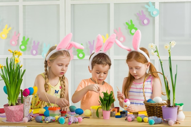 Cute kids painting Easter eggs at home