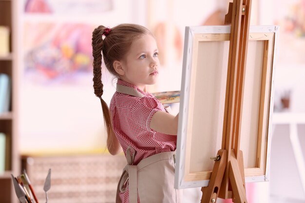 Cute little artist painting picture in studio