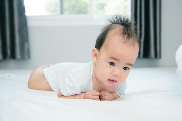 Cute little asian baby on bed with soft blanket indoors