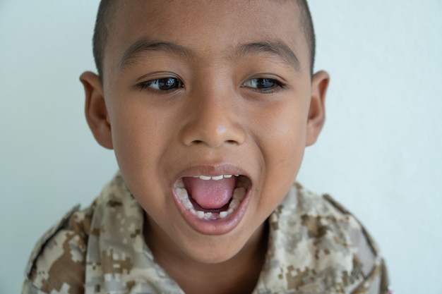 Piccoli denti asiatici svegli di sorriso e di manifestazione del ragazzo rotti