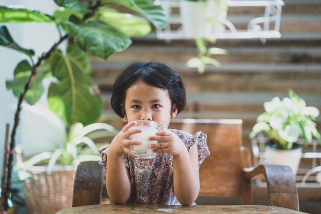 Cute little Asian girl drinking fresh organic milk at garden