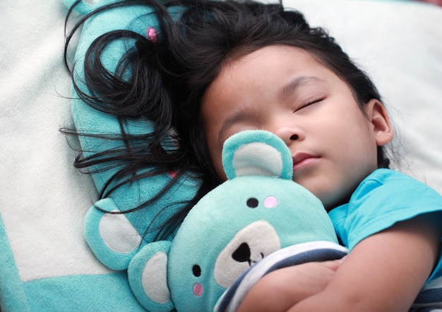 cute little asian girl sleep and hug teddy bear