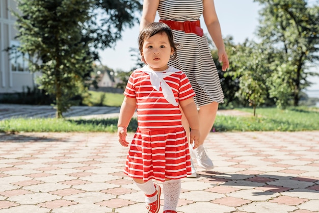 Cute little Asian girl in a striped dress in nature