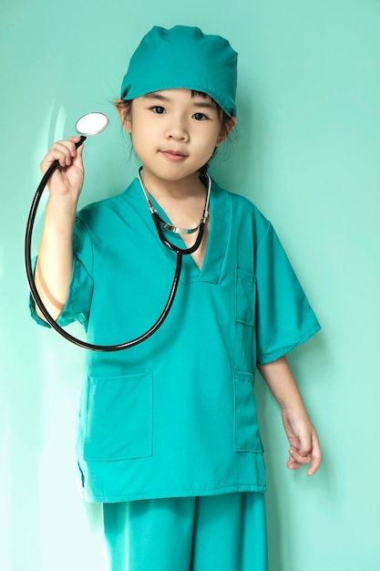 Cute little asian girl wears medical uniform holding a stethoscope playing doctor Happy child pretending to be a pediatrician