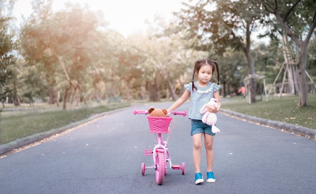 Cute little asian girl with a doll in the park