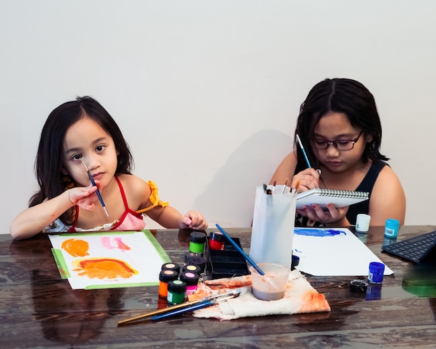 Милые маленькие азиатские братья и сестры рисуют картину в домашней студии