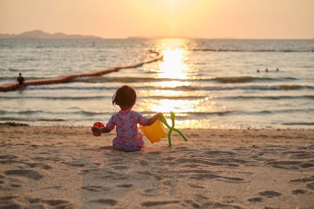 夏休みの熱帯のビーチでビーチおもちゃで遊ぶかわいい小さなアジアの幼児の女の子