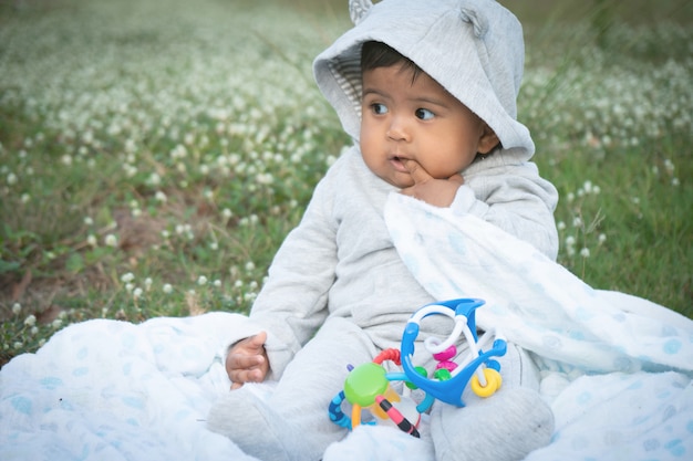 写真 白い花の庭に座っているかわいいアシナ赤ちゃん