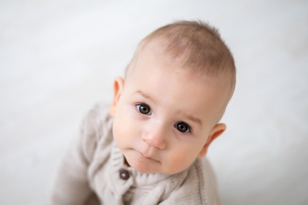 Cute little baby boy large portrait of a child with brown eyes and blond hair in a pastel knitted suit