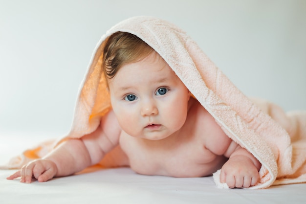 Cute little baby covered with a bath towel lying on tummy, after bathing.