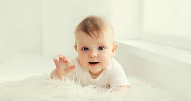 Cute little baby crawling on the floor in white room at home