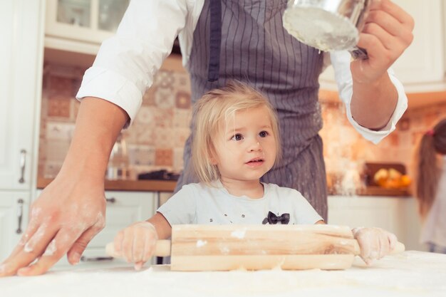 Cute little baby girl 2 years old cook apple pie for dinner Kid prepares the dough at home