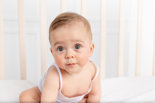 Cute little baby girl sitting in bed