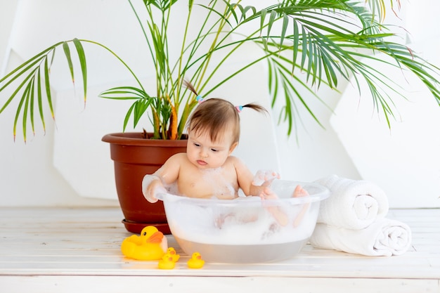 Piccola neonata sveglia che cattura un bagno