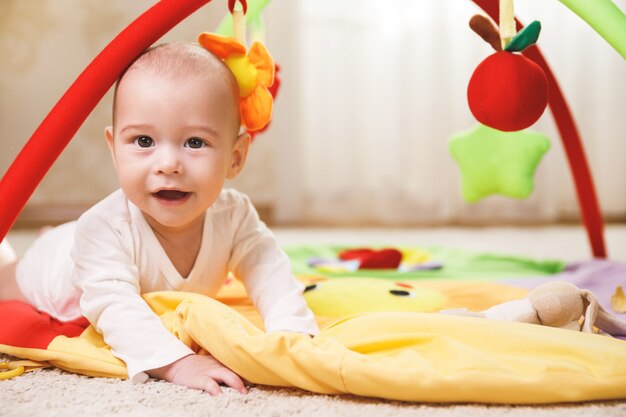 Cute little baby is playing on the activity mat