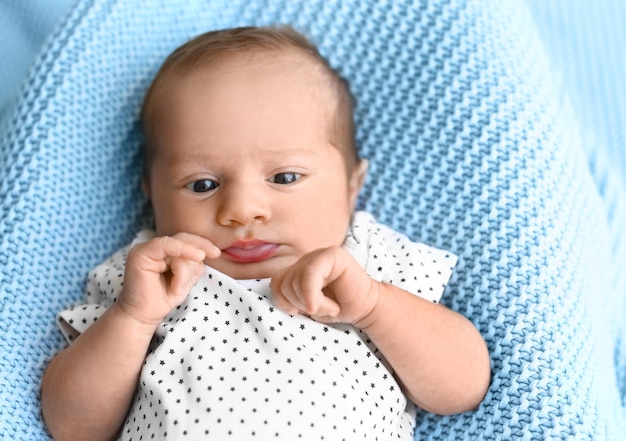 Cute little baby lying on light blue plaid top view