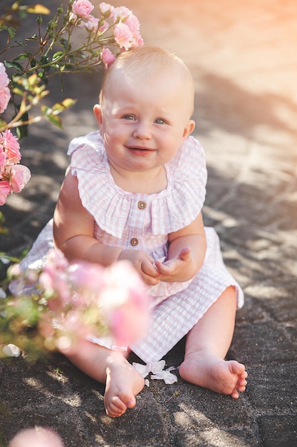 屋外でかわいい赤ちゃんバラのかわいい小さな女の子が庭でかわいい子供