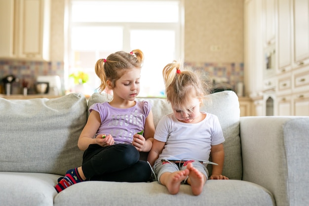 Cute little baby playing digital tablet sitting on the sofa. Parenting control. Child internet safety concept.