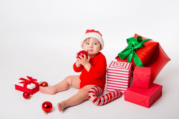 Cute little baby in a Santa costume with gifts