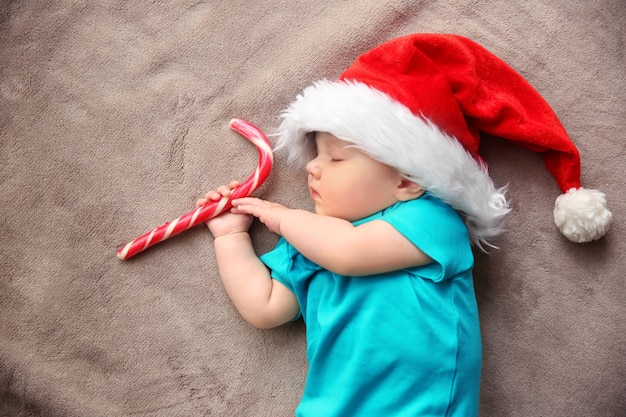 Cute little baby in Santa hat sleeping on fabric