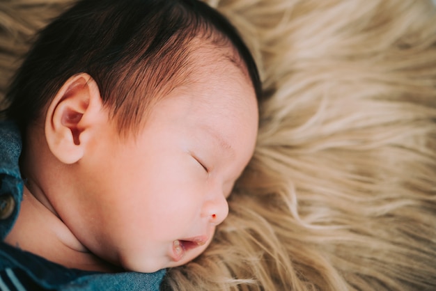 Piccolo bambino sveglio che dorme sul plaid morbido